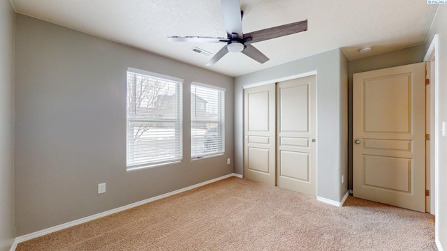 unfurnished bedroom featuring a closet, light carpet, and ceiling fan