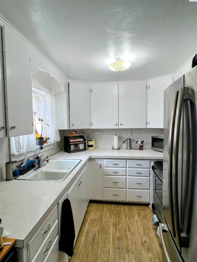 1836 W Park St, Pasco, WA 99301 - kitchen with stainless steel appliances, light wood-style flooring, white cabinetry, light countertops, and a textured ceiling