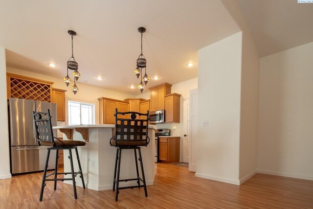 1205 SW Hannah St, Pullman, WA 99163 - kitchen with a kitchen island, a kitchen bar, light wood-type flooring, light countertops, and stainless steel appliances