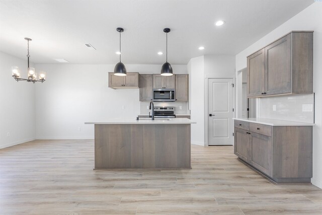 kitchen featuring an inviting chandelier, light countertops, light wood finished floors, recessed lighting, and stainless steel appliances