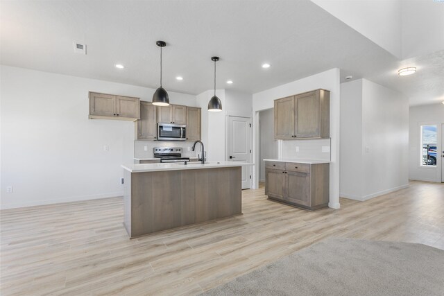 kitchen featuring light countertops, light wood finished floors, baseboards, and stainless steel appliances