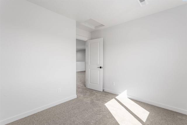 empty room featuring visible vents, baseboards, attic access, and light colored carpet