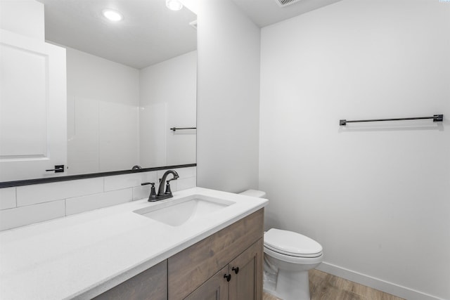 bathroom with visible vents, baseboards, toilet, vanity, and wood finished floors