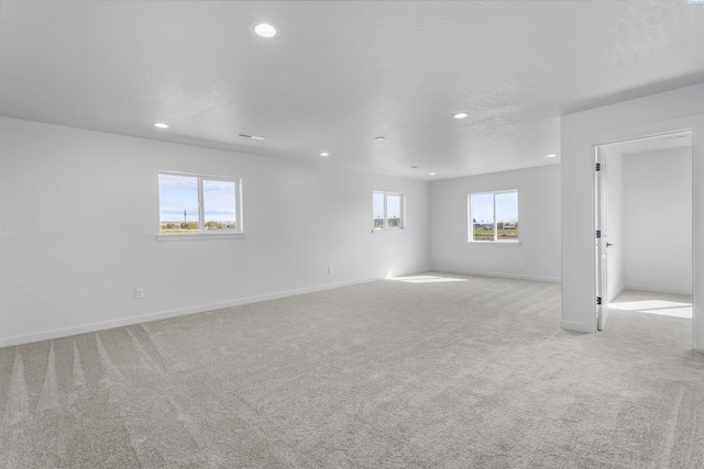 unfurnished room with light carpet, recessed lighting, and baseboards