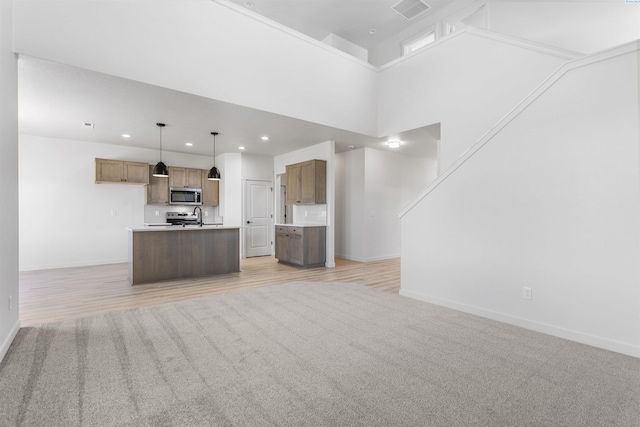 unfurnished living room featuring visible vents, baseboards, a sink, recessed lighting, and light wood finished floors