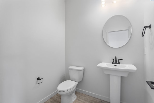 bathroom with baseboards, a sink, toilet, and wood finished floors