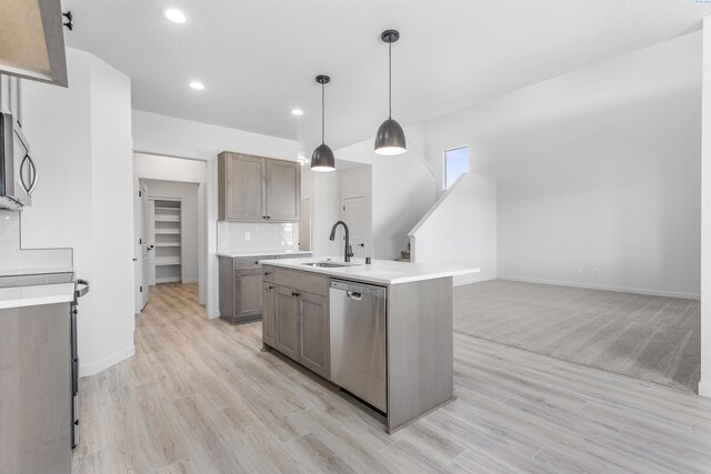 kitchen featuring recessed lighting, light countertops, light wood-style floors, stainless steel appliances, and a sink