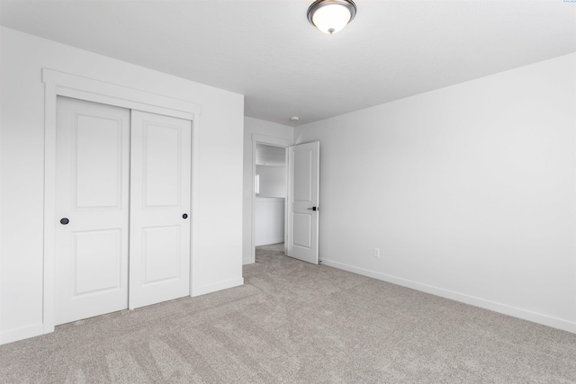 unfurnished bedroom with carpet, a closet, and baseboards