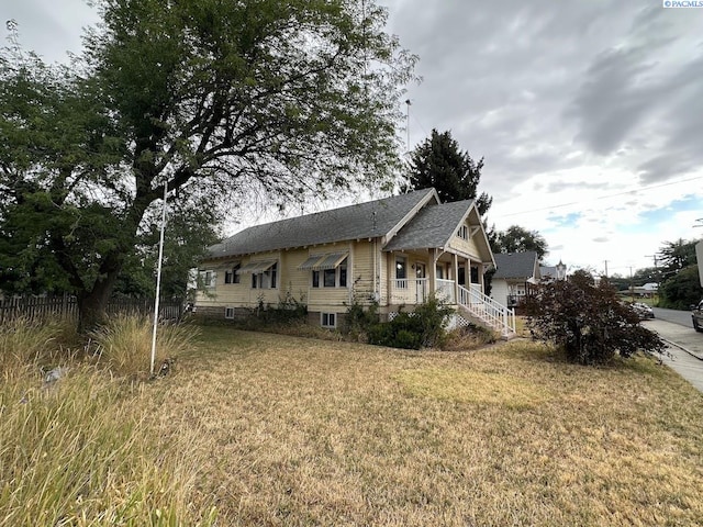 view of side of home with a yard and covered porch