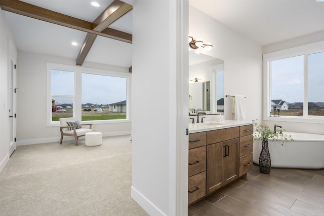 bathroom with beamed ceiling, vanity, and a bath