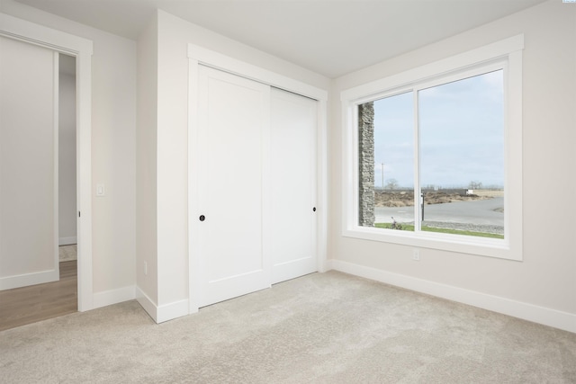 unfurnished bedroom featuring light carpet and a closet