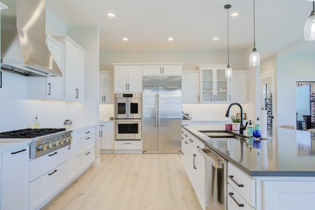 kitchen featuring sink, appliances with stainless steel finishes, hanging light fixtures, extractor fan, and white cabinets