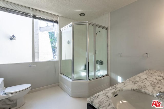 full bathroom featuring toilet, a textured ceiling, vanity, and shower / bath combination with glass door