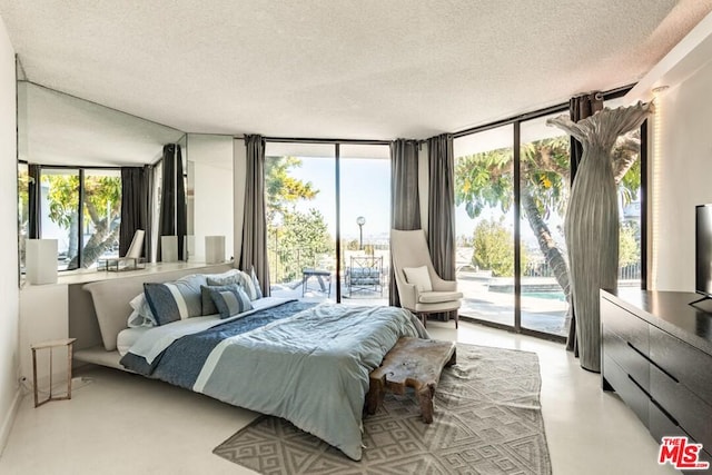 bedroom with a textured ceiling, a wall of windows, access to outside, and multiple windows