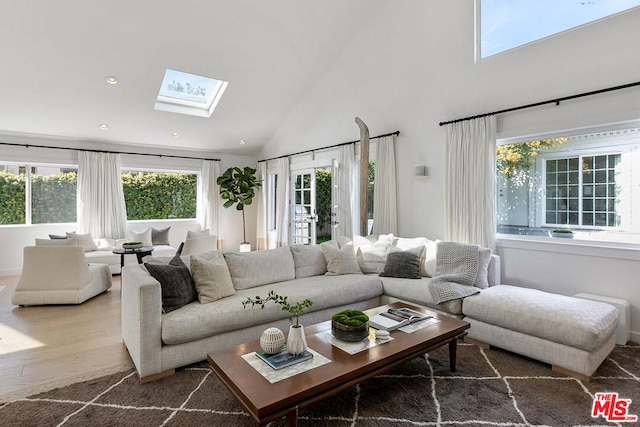 living room featuring a skylight, high vaulted ceiling, and wood-type flooring