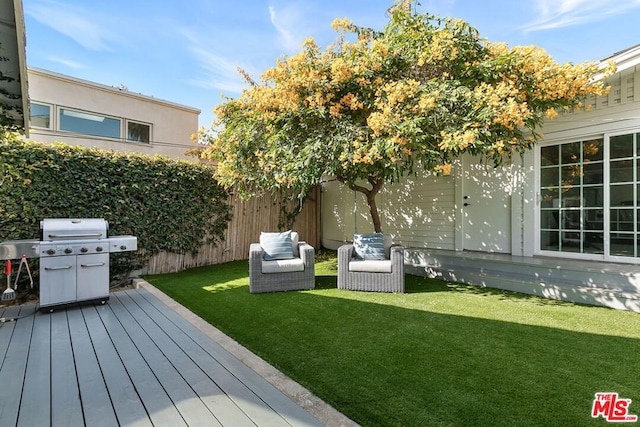 wooden deck featuring a grill, an outdoor living space, and a lawn