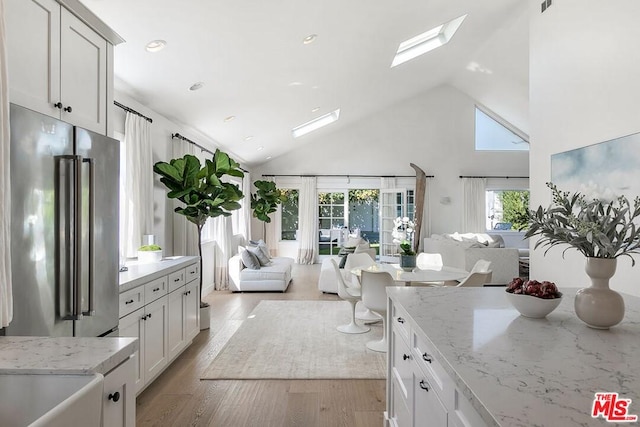 bathroom featuring high vaulted ceiling, a skylight, vanity, and wood-type flooring