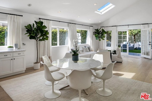 dining space featuring french doors, light hardwood / wood-style flooring, plenty of natural light, and a skylight