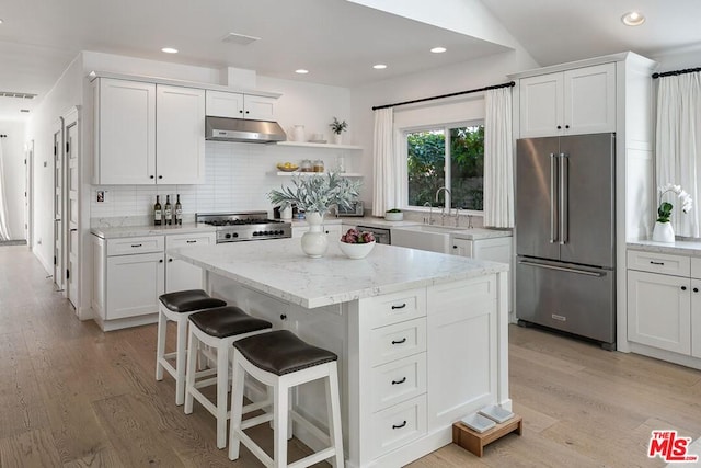 kitchen featuring high end fridge, white cabinets, and a center island