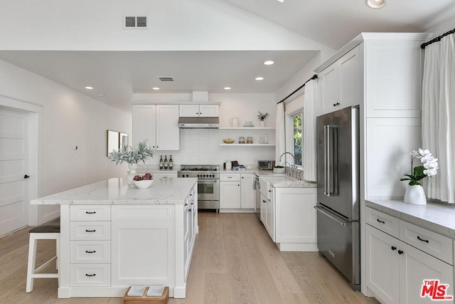 kitchen featuring high end appliances, a center island, white cabinets, and light wood-type flooring