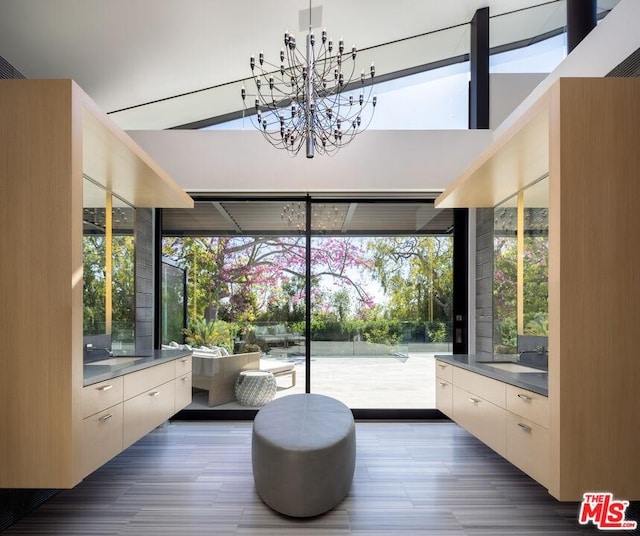 sunroom / solarium with a notable chandelier, sink, vaulted ceiling, and plenty of natural light