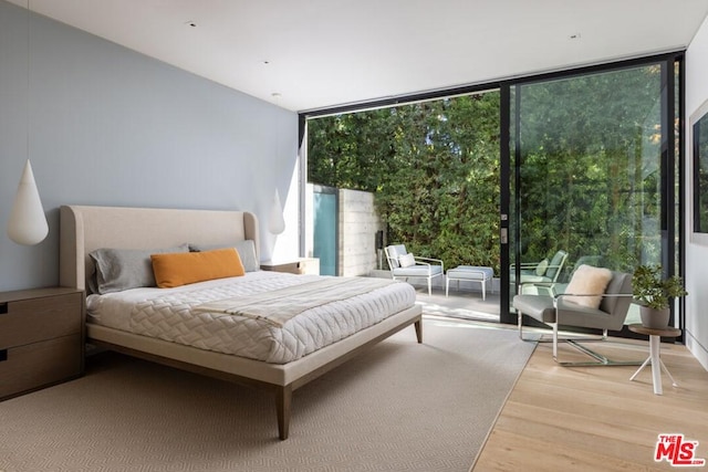 bedroom with expansive windows, multiple windows, and light hardwood / wood-style flooring