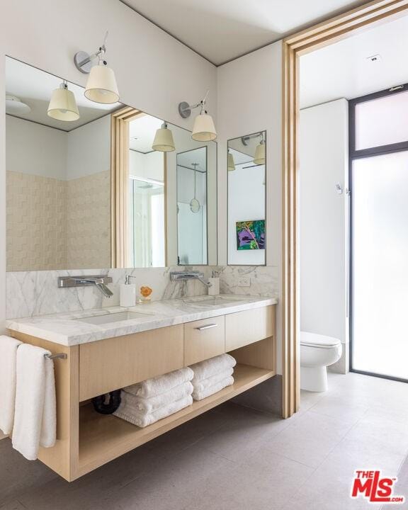 bathroom with a healthy amount of sunlight, tile floors, toilet, and vanity with extensive cabinet space