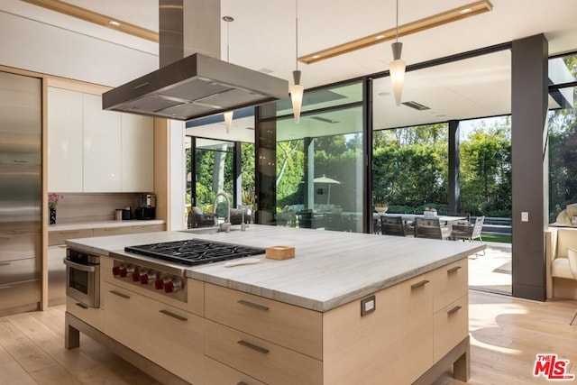 kitchen with decorative light fixtures, a kitchen island, floor to ceiling windows, light hardwood / wood-style flooring, and island range hood