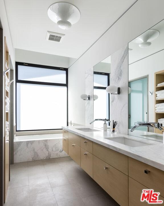 bathroom with double sink, tile flooring, plenty of natural light, and vanity with extensive cabinet space