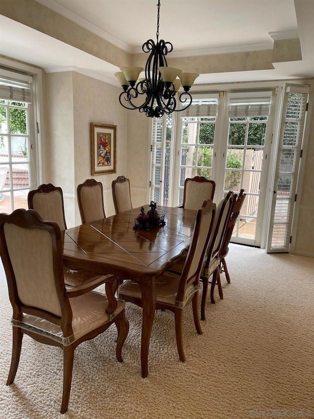 dining area featuring an inviting chandelier, a wealth of natural light, carpet floors, and ornamental molding