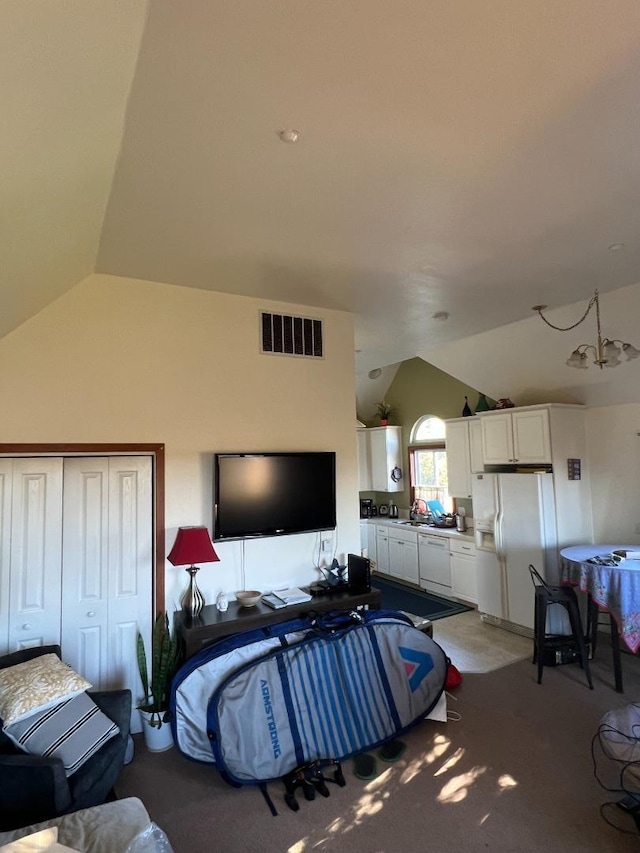 carpeted bedroom featuring white refrigerator with ice dispenser, vaulted ceiling, a closet, and a notable chandelier