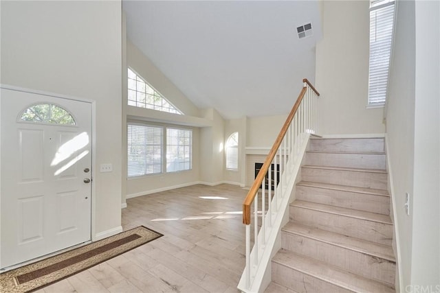 foyer with light hardwood / wood-style flooring and high vaulted ceiling