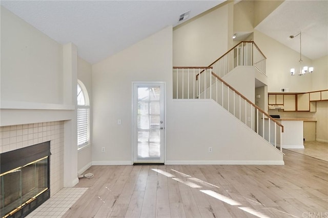 unfurnished living room with high vaulted ceiling, light hardwood / wood-style floors, and a fireplace