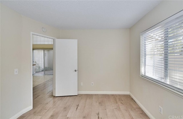 spare room featuring light hardwood / wood-style flooring, plenty of natural light, and a textured ceiling