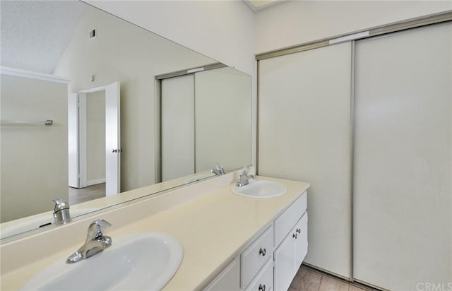 bathroom featuring dual sinks, large vanity, and vaulted ceiling