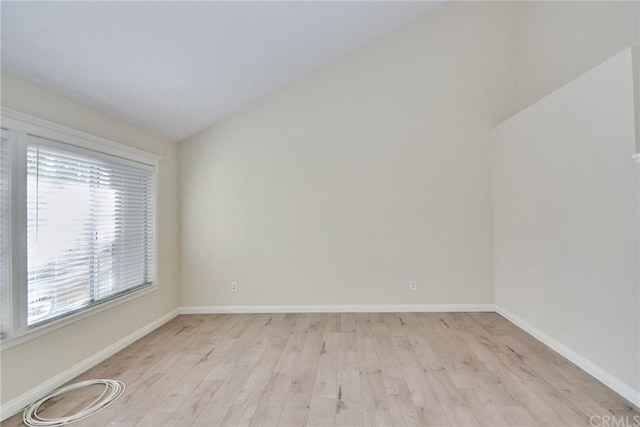 spare room with light hardwood / wood-style flooring and vaulted ceiling