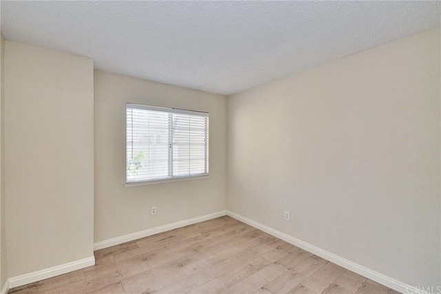 unfurnished room with a textured ceiling and light hardwood / wood-style floors