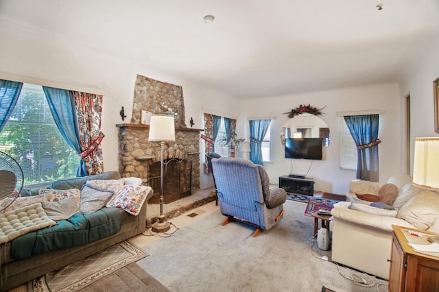 living room featuring a stone fireplace and a healthy amount of sunlight