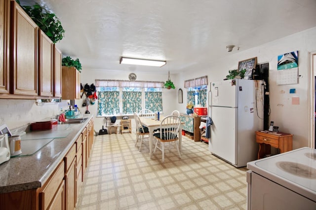 kitchen with dark stone counters, light tile floors, stove, and white fridge