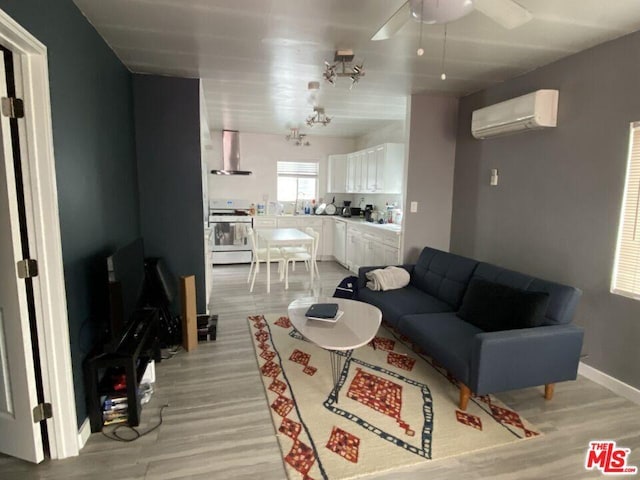 living room featuring ceiling fan, light hardwood / wood-style flooring, and a wall unit AC