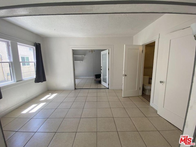 unfurnished bedroom with a closet, a textured ceiling, and light tile flooring