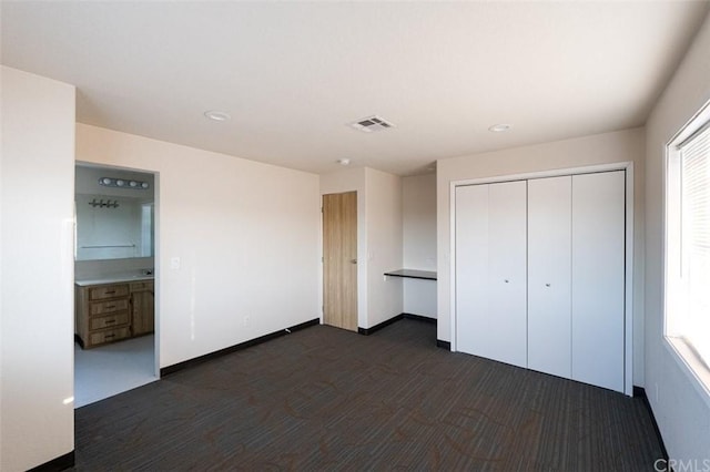 unfurnished bedroom with ensuite bathroom, a closet, and dark hardwood / wood-style floors