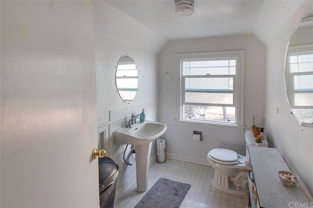 bathroom with toilet, sink, vaulted ceiling, and tile flooring