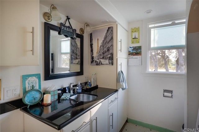 kitchen with white cabinets, tile floors, and sink