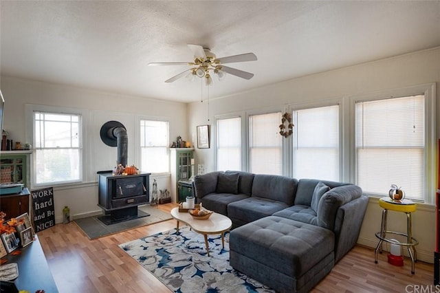 living room featuring ceiling fan, a wood stove, and light hardwood / wood-style flooring