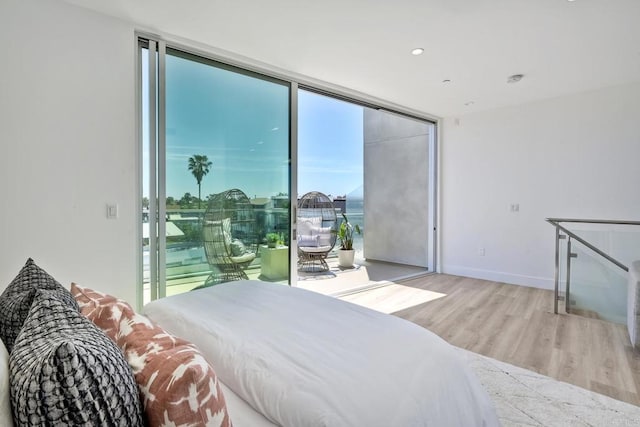 bedroom with floor to ceiling windows and light wood-type flooring