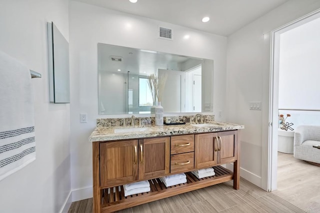 bathroom featuring hardwood / wood-style floors, double sink, and vanity with extensive cabinet space