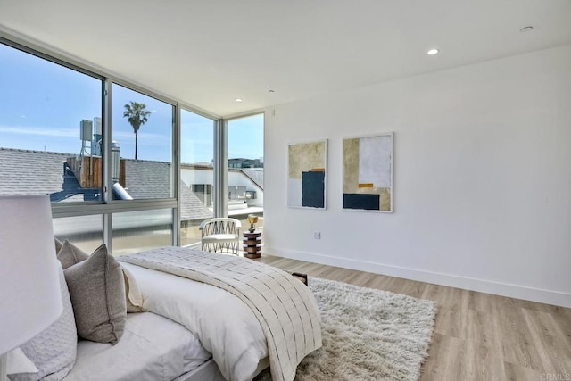 bedroom featuring expansive windows, multiple windows, and light wood-type flooring