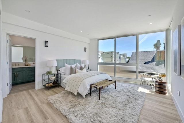 bedroom featuring connected bathroom, sink, and light hardwood / wood-style floors