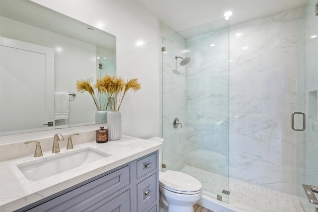 bathroom featuring toilet, vanity, and a shower with door